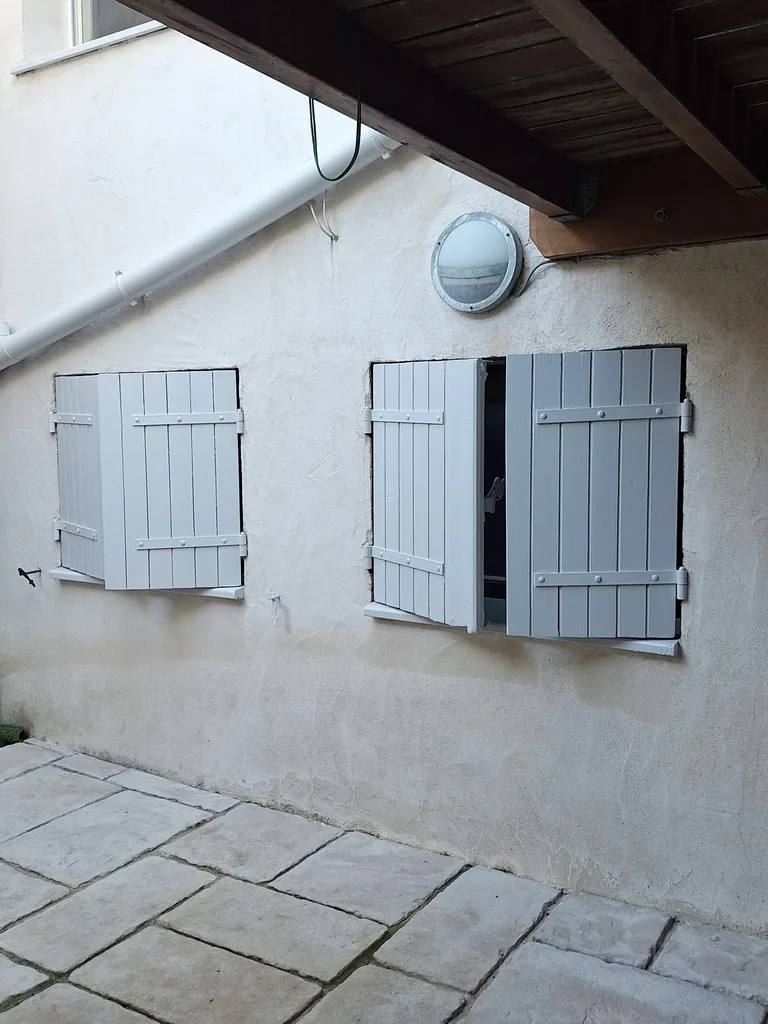 Deux fenêtres en rez-de-cour avec volets bois repeints en gris clair, rue Condorcet à Bordeaux