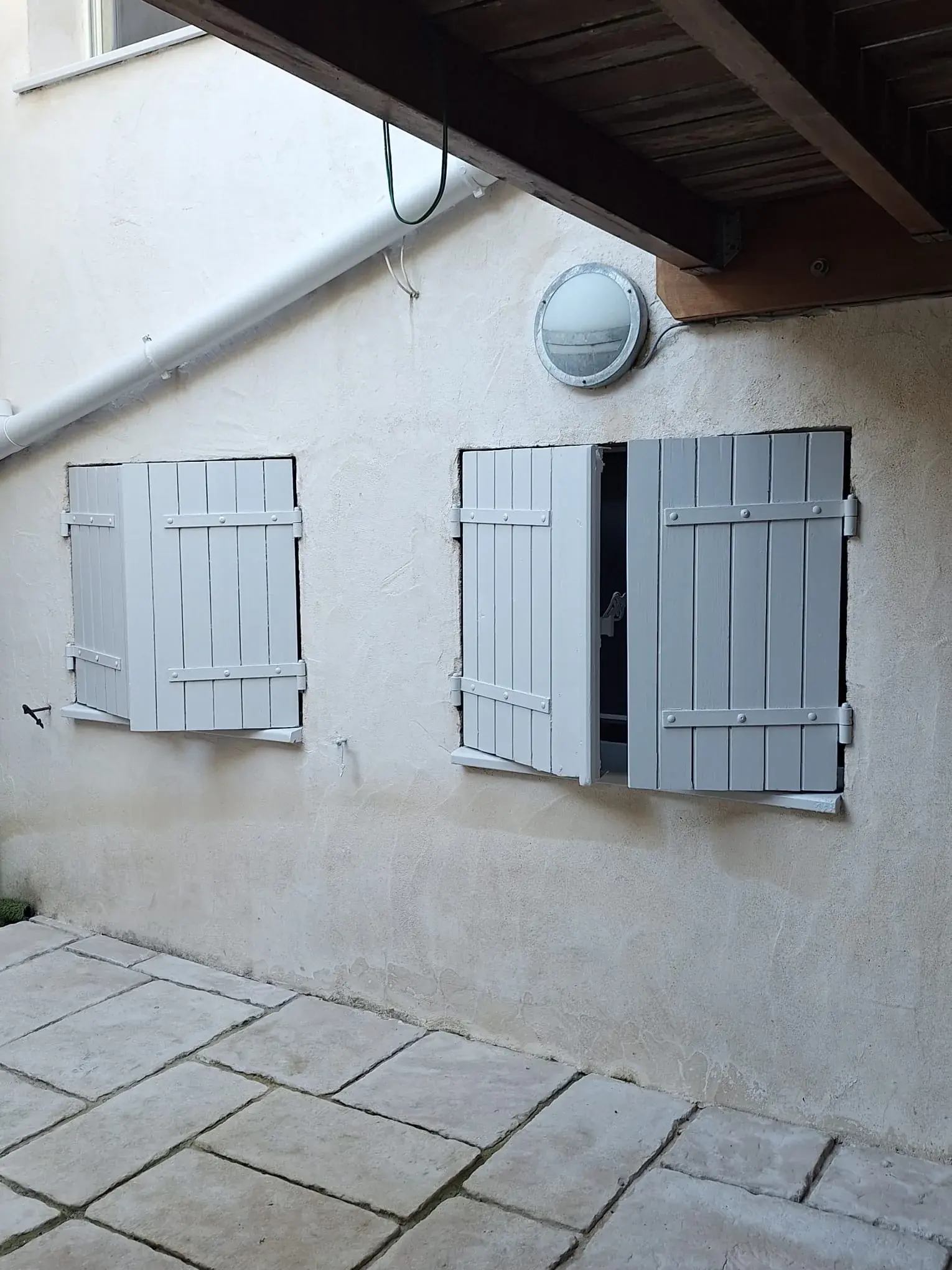 Deux fenêtres en rez-de-cour avec volets bois repeints en gris clair, rue Condorcet à Bordeaux