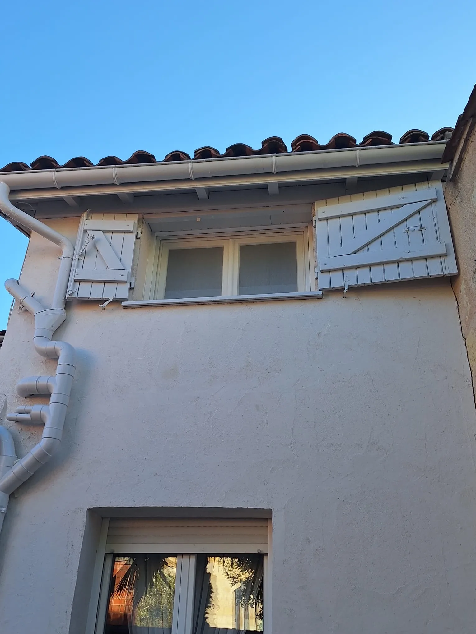 Volets bois repeints en gris clair sur une lucarne de toit, avec gouttière traitée, rue Condorcet à Bordeaux